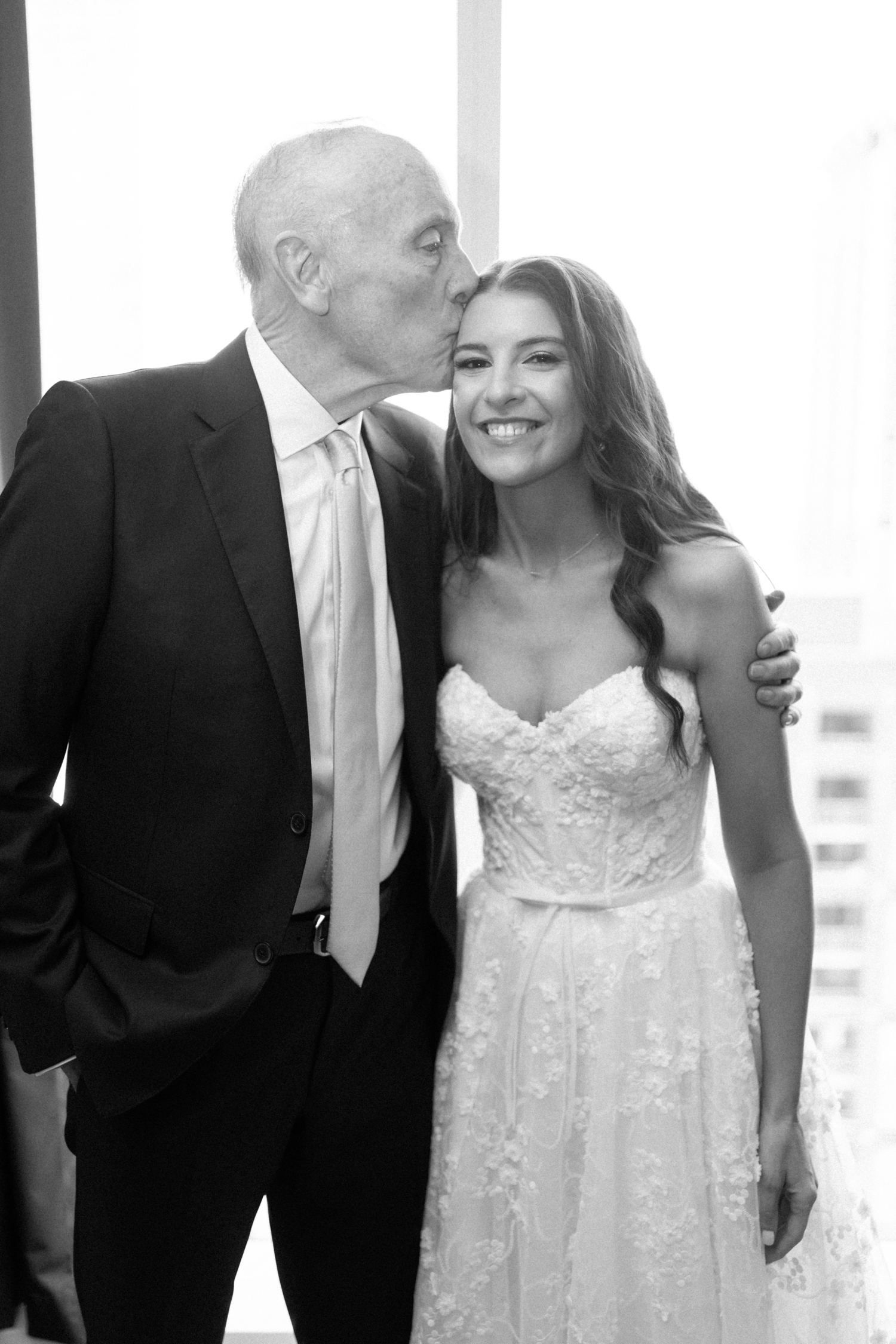 Father of bride kissing bride on head at Revel motor row Chicago wedding, photography by Allison Francois