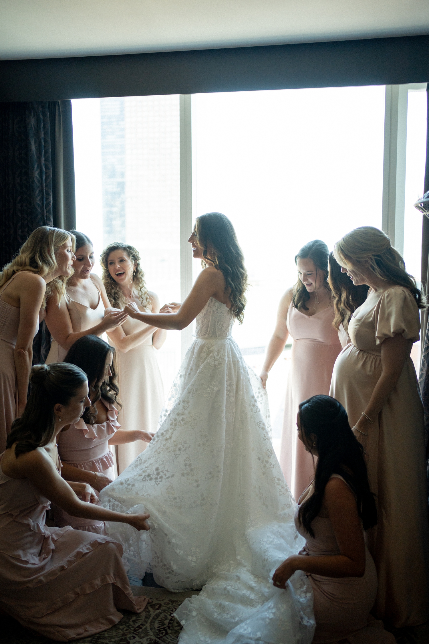 Bride surrounded by bridesmaids getting ready at Revel motor row Chicago wedding, photography by Allison Francois