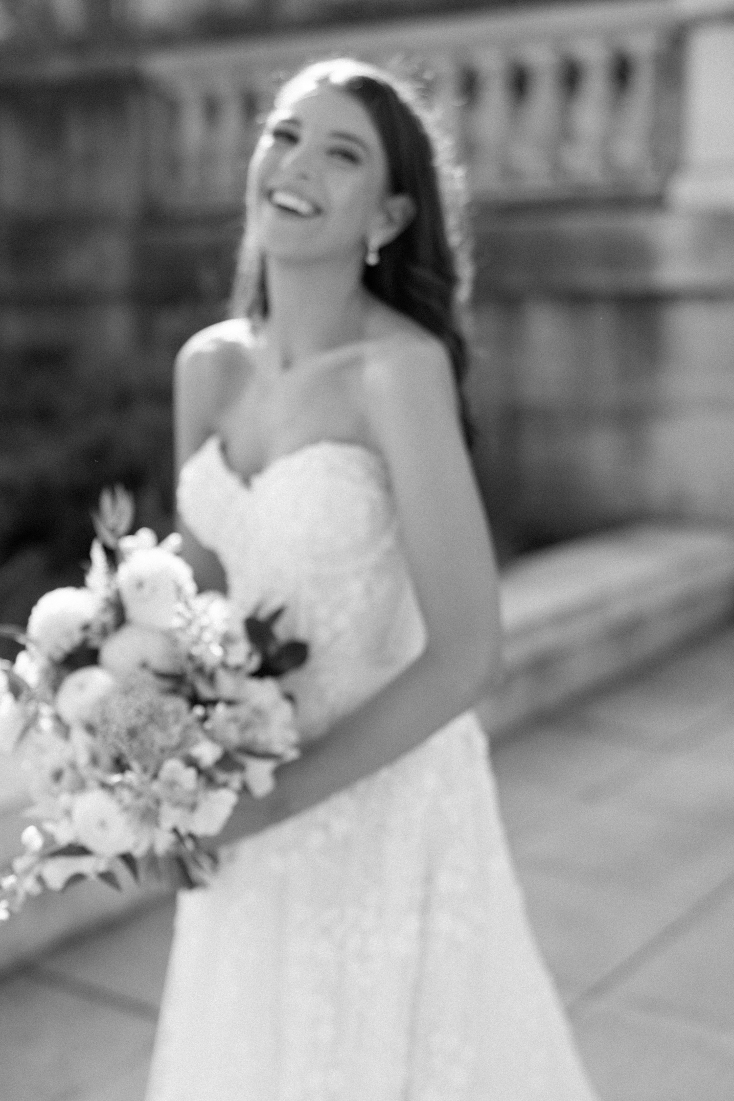 Bride holding bouquet and smiling at Revel motor row, photography by Allison Francois
