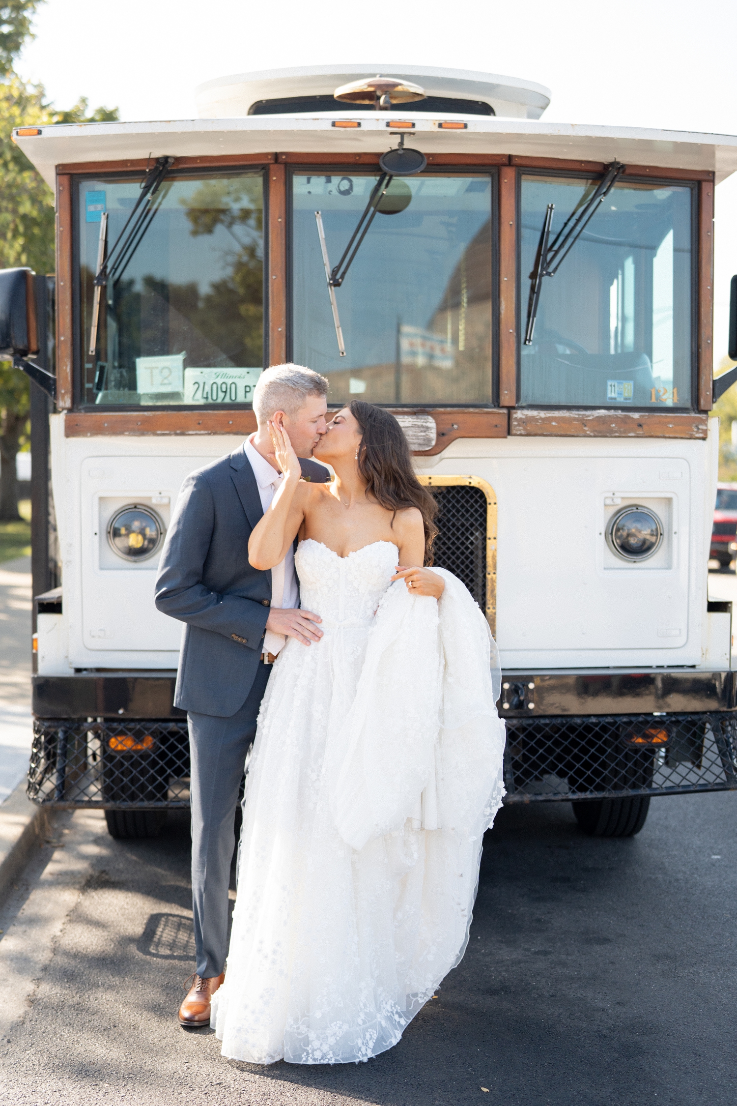 Bride and groom kissing in front of trolley at Revel motor row, photography by Allison Francois